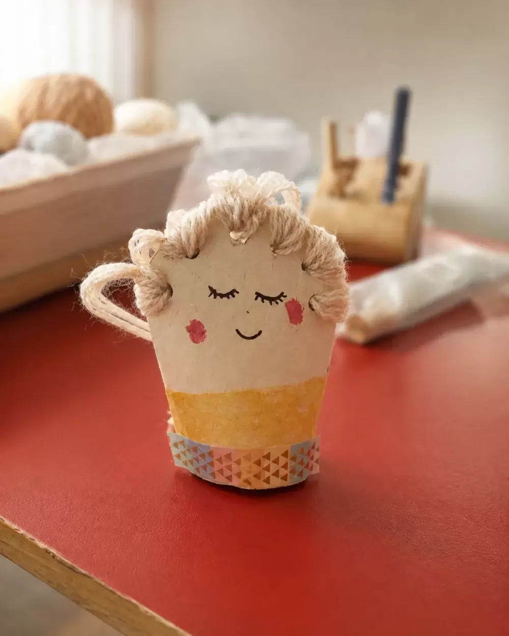 Taza de cartón con carita bordada y flequillo de lana, proyecto de El Club del Nudo